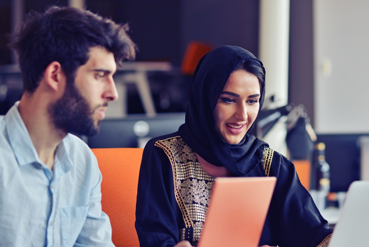 Multiracial contemporary business people working connected with technological devices like tablet and laptop, talking together - finance, business, technology concept